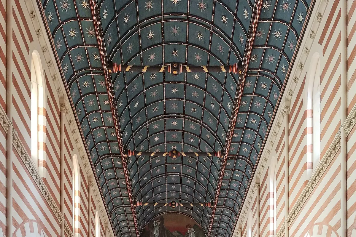 Die tiefblaue Tonnendecke der Kirche, besetzt mit goldenen Sternen und gerahmt von rot-weiß gestreiften Wänden.